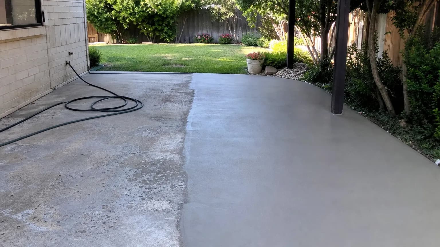 Worn concrete patio half covered with a fresh smooth gray resurfacing overlay, with a clear line between the pitted old surface and the new
