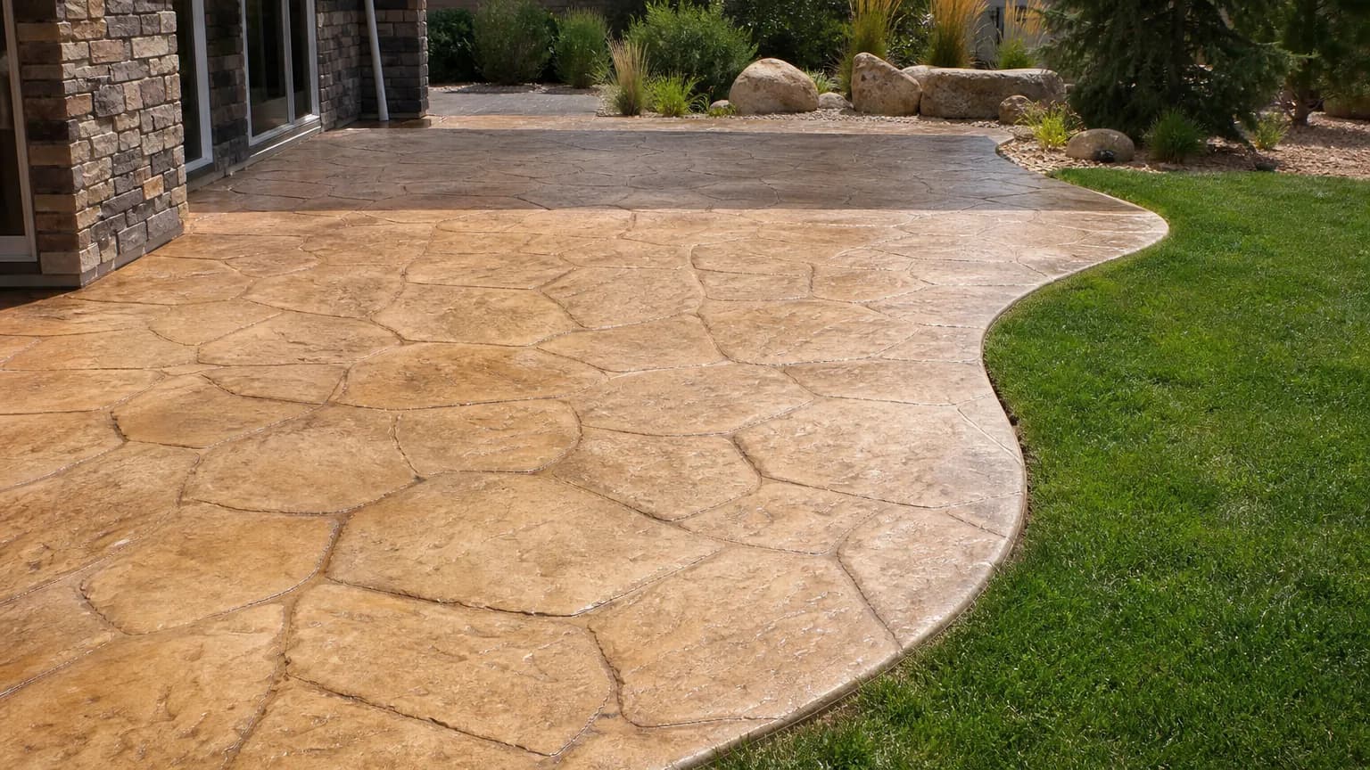 Stamped concrete patio in a random stone pattern with a sandstone tan base, darker brown antiquing in the joints and a light sealer sheen